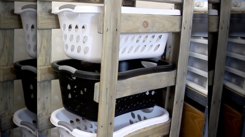 A finished DIY laundry basket organizer is staged with two white and one black laundry baskets.