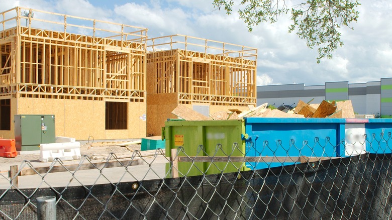 A bin of scrap wood is seen in the foreground of a construction site for new apartments
