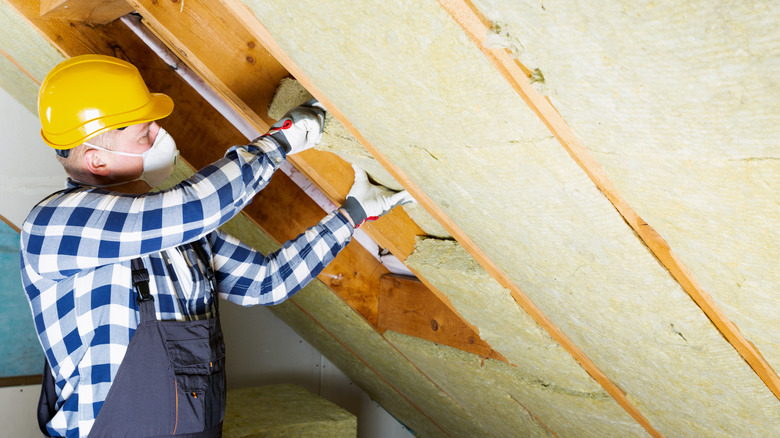 Man working in attic with protective gear on