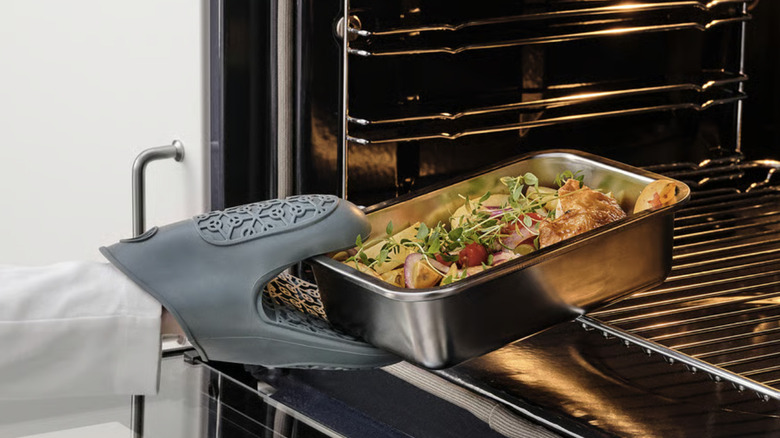 Person puts a stainless steel food storage container into the oven to reheat.